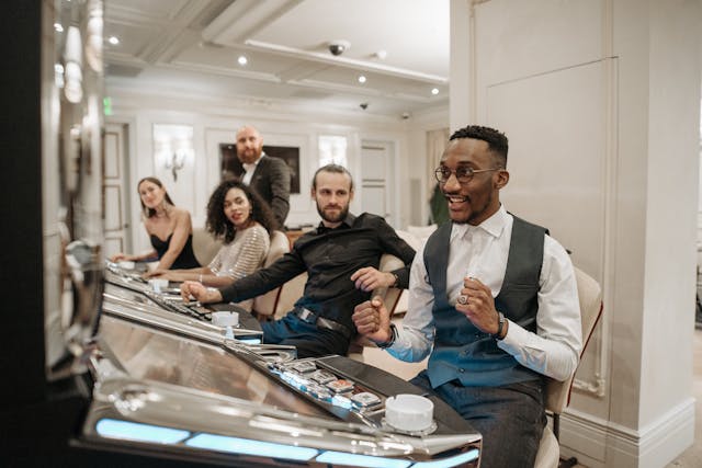 A photo of a man responsibly celebrating a win on a slot machine with onlookers in the background.